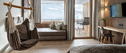 Modernes Hotelzimmer mit Hängesessel und Bergblick im Naturhotel Sonnberghof