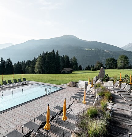 Outdoor-Pool und Liegestühle des Sonnberghof Naturhotels mit Blick auf die Alpen