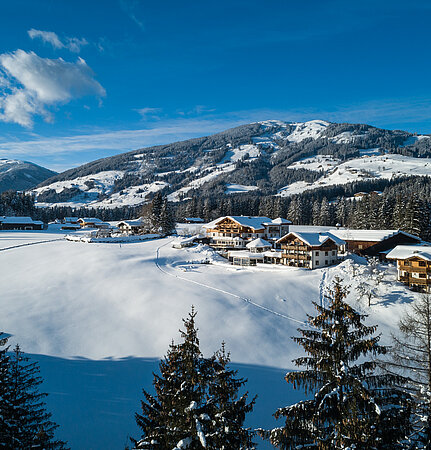Luftaufnahme des Sonnberghof Naturhotels im Winter mit umliegenden Bergen.
