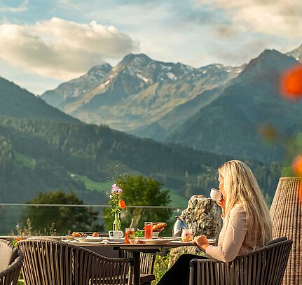 Frau genießt Frühstück auf Terrasse mit Bergblick im Sonnberghof Naturhotel