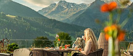 Frau genießt Frühstück auf Terrasse mit Bergblick im Sonnberghof Naturhotel