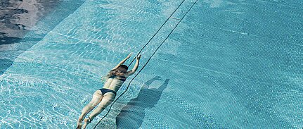 Frau genießt das Schwimmen im Outdoorpool des Wellnesshotels Sonnberghof